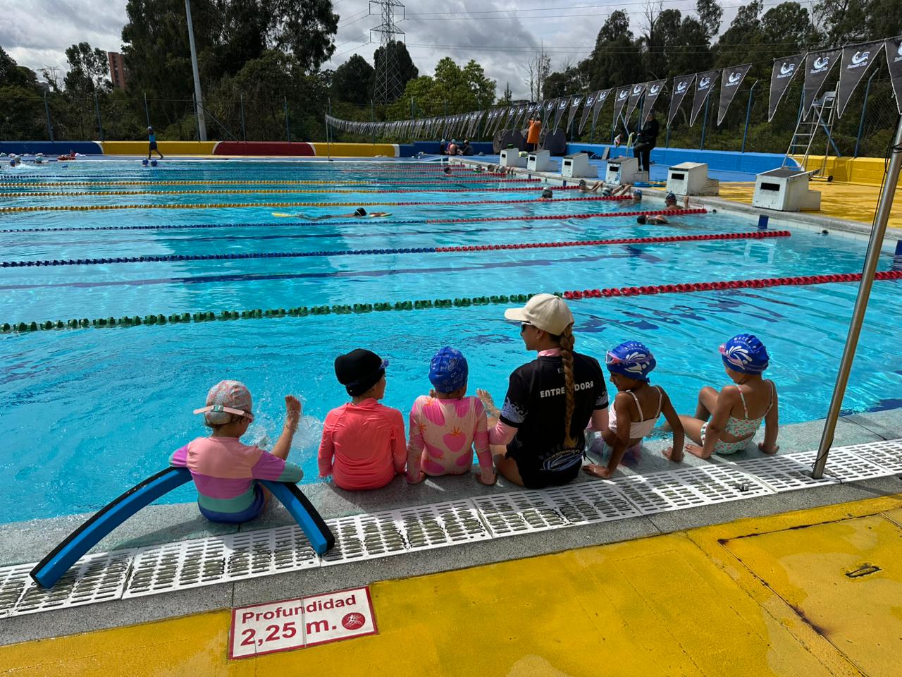 Entrenadora con grupo de niños junto a la piscina